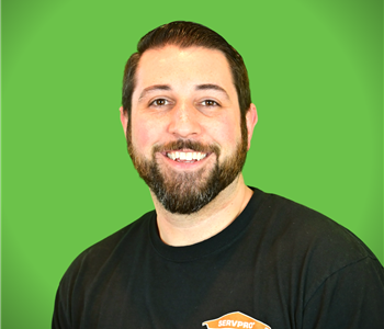 A male SERVPRO employee smiles in front of a green background.