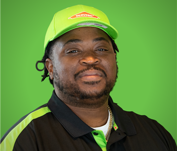 A male SERVPRO employee smiles infront of a green background.