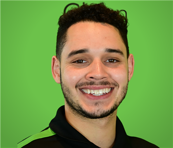 Male SERVPRO Employee smiling in front of a green background.