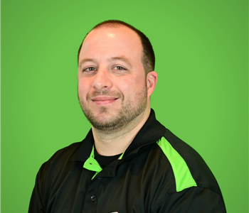 A male SERVPRO employee smiles in front of a green background.