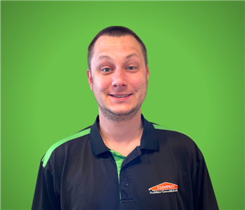 A male SERVPRO employee smiles in front of a green background.